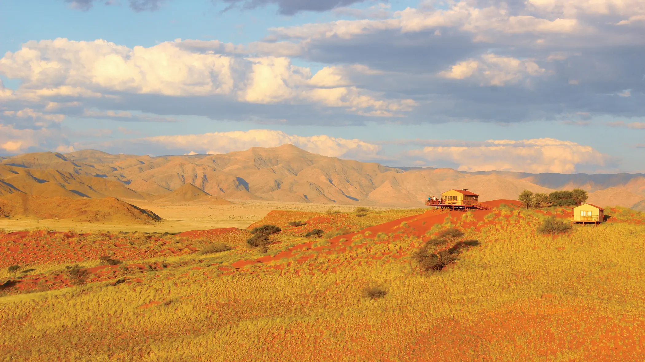 Namib plains at golden hour, with a distant camp below the mountains